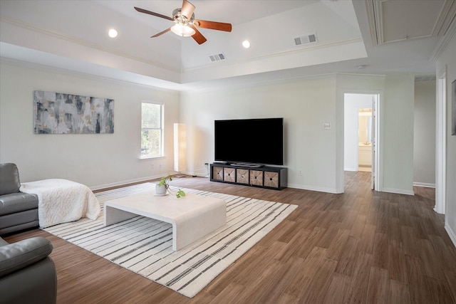 living room with ceiling fan, ornamental molding, a tray ceiling, and dark hardwood / wood-style floors