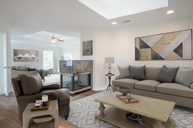 living room with ceiling fan, ornamental molding, a high end fireplace, and wood-type flooring