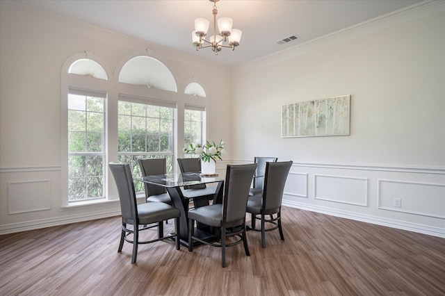 dining space featuring wood-type flooring, a chandelier, and ornamental molding