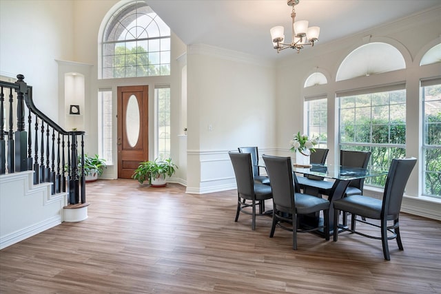 dining area featuring crown molding, a wealth of natural light, hardwood / wood-style flooring, and a notable chandelier