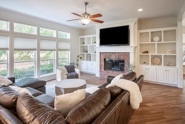 living room with a fireplace, ceiling fan, crown molding, and a wealth of natural light