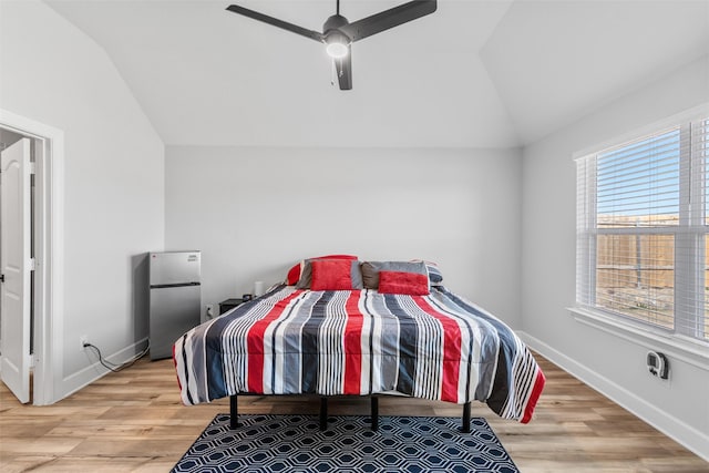 bedroom with ceiling fan, multiple windows, lofted ceiling, and stainless steel refrigerator