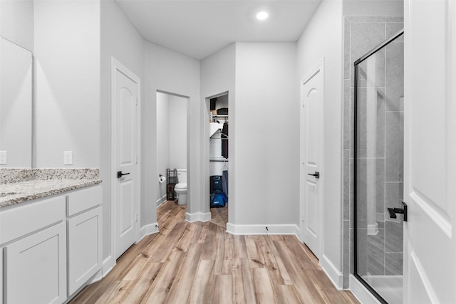 bathroom featuring toilet, a shower with shower door, wood-type flooring, and vanity