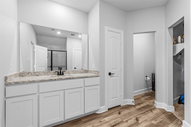 bathroom with a shower with door, vanity, and wood-type flooring