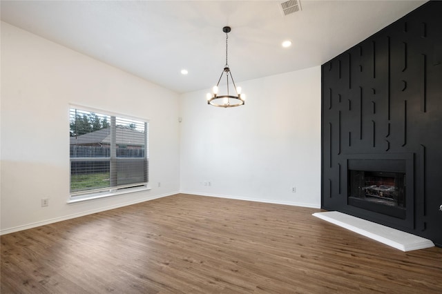 unfurnished dining area featuring a fireplace, a chandelier, and dark wood-type flooring