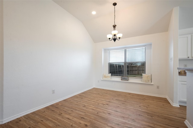 unfurnished dining area featuring lofted ceiling, a chandelier, and light hardwood / wood-style floors