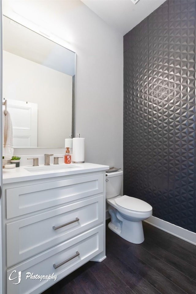 bathroom with toilet, vanity, and hardwood / wood-style flooring