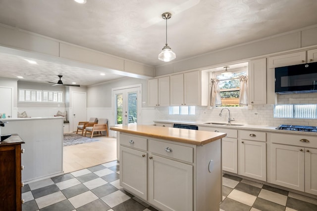 kitchen with stainless steel gas stovetop, ceiling fan, decorative light fixtures, white cabinets, and sink