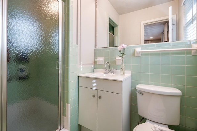 bathroom with an enclosed shower, vanity, tile walls, and toilet