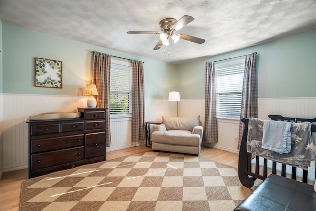 bedroom with light wood-type flooring, ceiling fan, and a textured ceiling