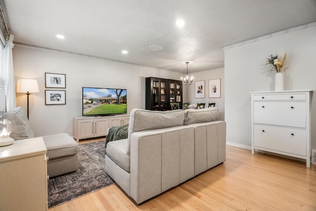 living room with a textured ceiling, light hardwood / wood-style flooring, and a notable chandelier