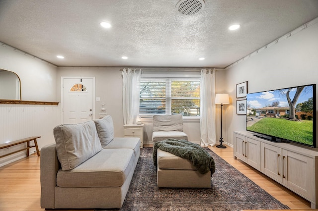 living room with a textured ceiling and light hardwood / wood-style flooring