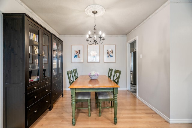 dining space with crown molding, a chandelier, and light hardwood / wood-style floors