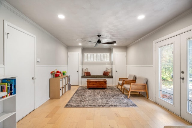 living area featuring light wood-type flooring, ceiling fan, ornamental molding, and french doors