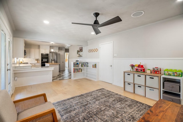 living room featuring ceiling fan, sink, crown molding, and light hardwood / wood-style floors