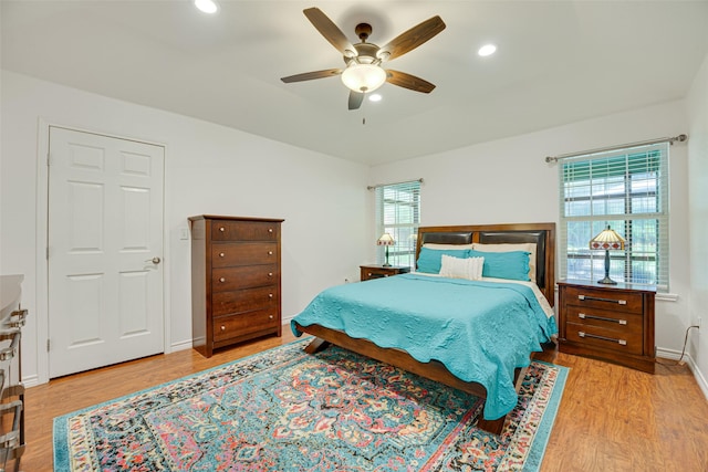 bedroom featuring ceiling fan, light hardwood / wood-style flooring, and multiple windows