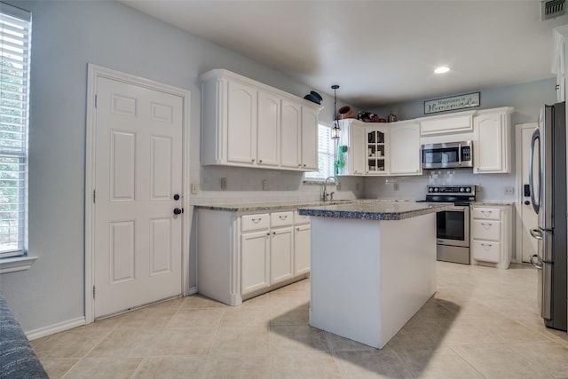 kitchen featuring sink, stainless steel appliances, white cabinetry, and a center island