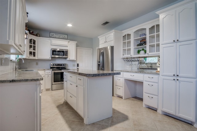 kitchen featuring stainless steel appliances, a center island, sink, and white cabinetry