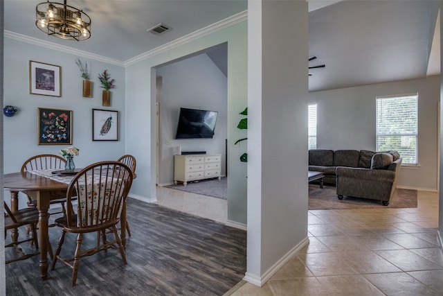 tiled dining area with crown molding and a chandelier