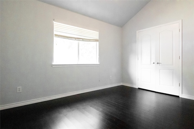 unfurnished bedroom featuring vaulted ceiling and dark wood-type flooring