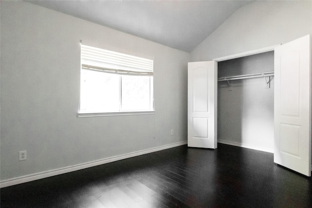 unfurnished bedroom featuring dark wood-type flooring, vaulted ceiling, and a closet