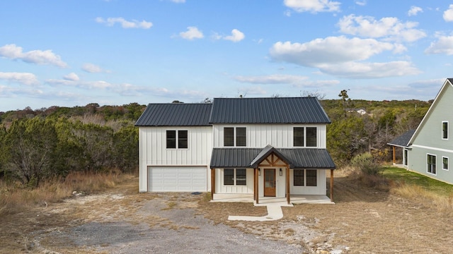 modern farmhouse style home featuring covered porch, metal roof, board and batten siding, and driveway