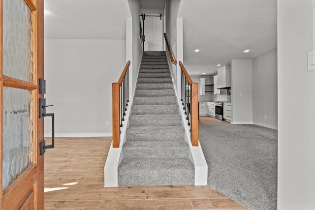 stairway featuring recessed lighting, wood finished floors, and baseboards