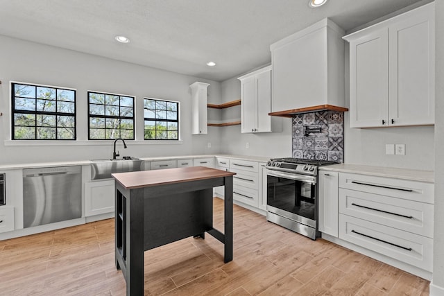 kitchen with custom exhaust hood, open shelves, stainless steel appliances, light countertops, and white cabinets