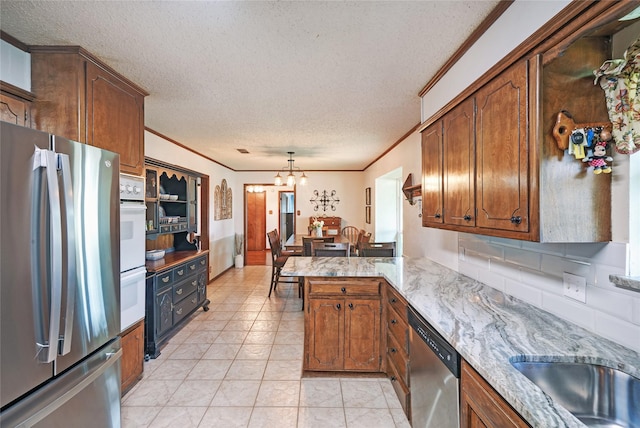 kitchen with kitchen peninsula, a textured ceiling, a chandelier, hanging light fixtures, and stainless steel appliances