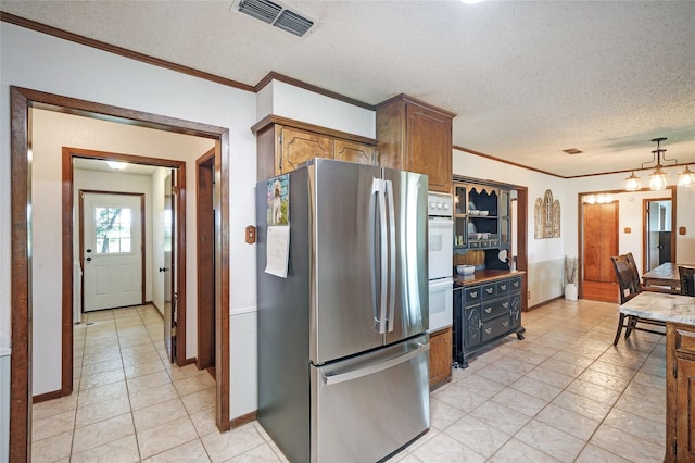 kitchen featuring stainless steel refrigerator, ornamental molding, a textured ceiling, and a notable chandelier