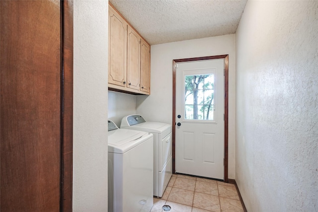 washroom with light tile patterned flooring, a textured ceiling, separate washer and dryer, and cabinets