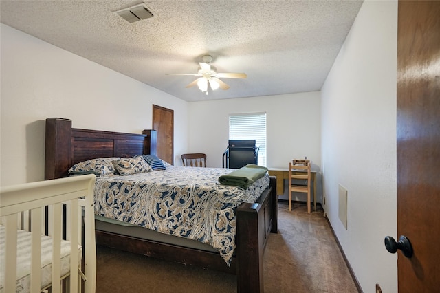 bedroom with a textured ceiling, dark colored carpet, and ceiling fan