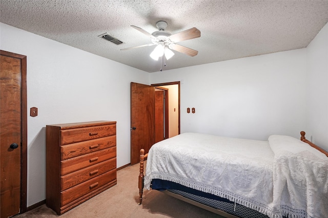 carpeted bedroom featuring ceiling fan and a textured ceiling