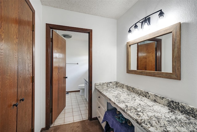 bathroom featuring toilet, tile patterned flooring, a textured ceiling, and vanity