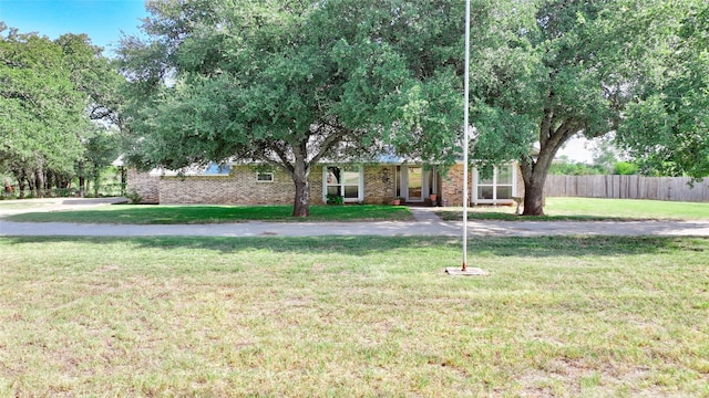 view of front of house featuring fence, a front lawn, and brick siding