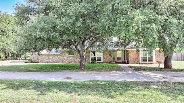 view of property hidden behind natural elements featuring a front yard