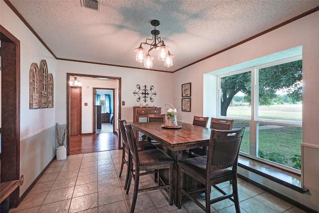 tiled dining space featuring an inviting chandelier and a textured ceiling