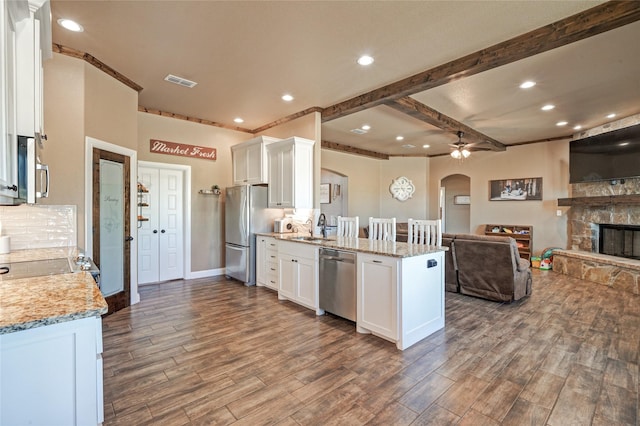 kitchen with stainless steel appliances, white cabinetry, ceiling fan, and light stone counters