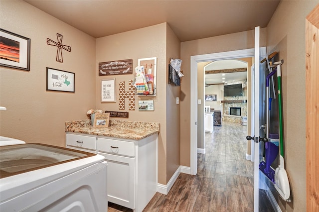 laundry room featuring dark hardwood / wood-style flooring and a stone fireplace