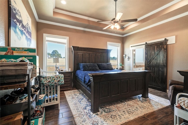 bedroom featuring ornamental molding, a barn door, a tray ceiling, and multiple windows