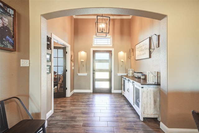 entryway featuring a towering ceiling, a notable chandelier, and crown molding