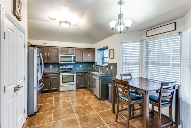 kitchen featuring sink, decorative light fixtures, lofted ceiling, tasteful backsplash, and appliances with stainless steel finishes