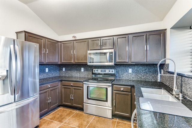 kitchen featuring stainless steel appliances, lofted ceiling, tasteful backsplash, and light tile patterned floors