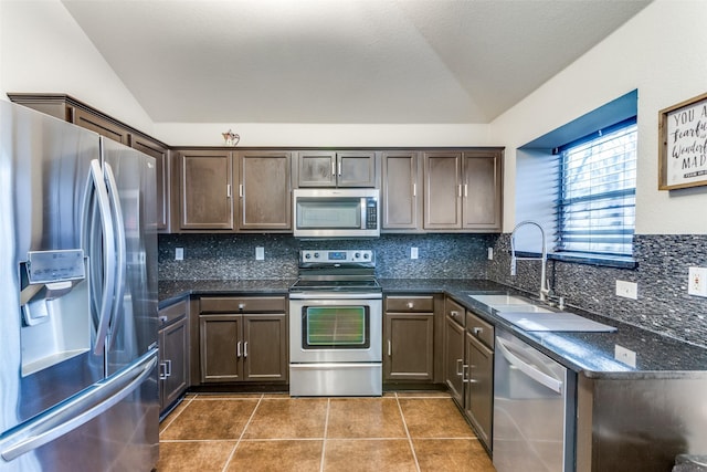 kitchen featuring sink, stainless steel appliances, lofted ceiling, and dark tile patterned flooring