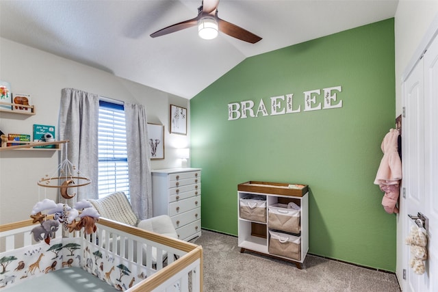 carpeted bedroom featuring a nursery area, ceiling fan, and vaulted ceiling