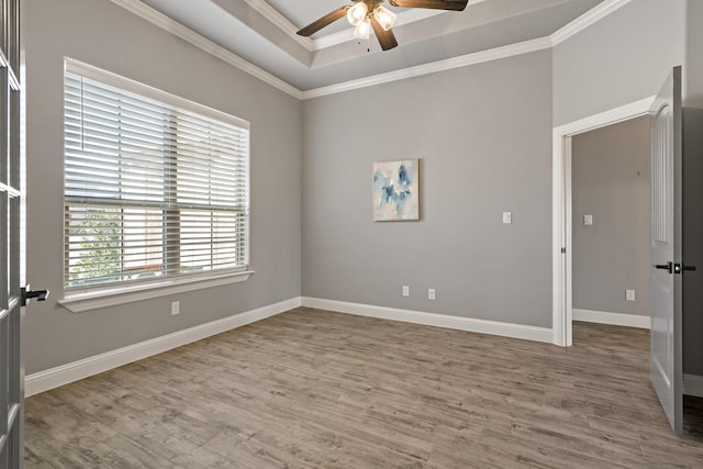 empty room featuring crown molding, ceiling fan, wood-type flooring, and a tray ceiling