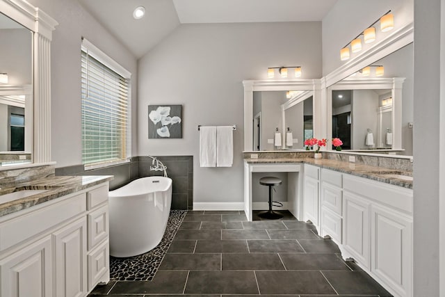 bathroom featuring lofted ceiling, vanity, tile patterned floors, and a tub