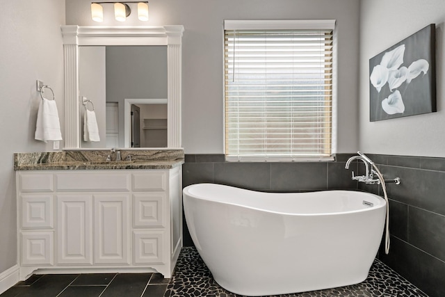 bathroom featuring a washtub, vanity, tile patterned floors, and tile walls