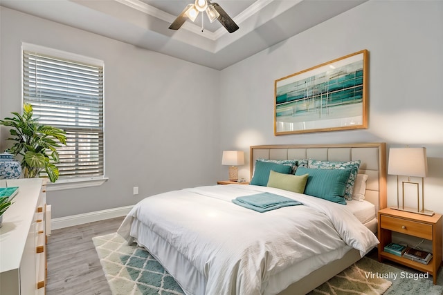 bedroom with a raised ceiling, ornamental molding, light hardwood / wood-style floors, and ceiling fan