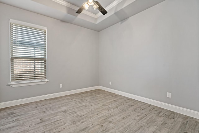 unfurnished room featuring ornamental molding, a raised ceiling, ceiling fan, and light wood-type flooring